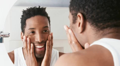 hudvård för män - man framför spegeln som känner på sitt skägg
