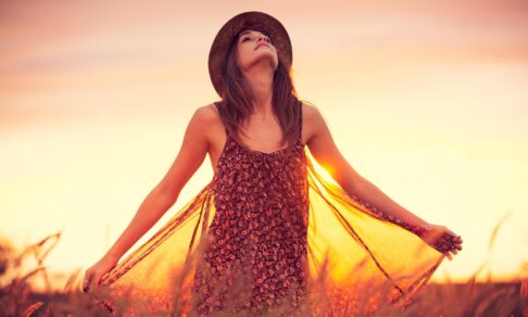 Det rigtige valg af olie - kvinde i marken med solnedgang i baggrunden - hovedet holdt højt mod himlen